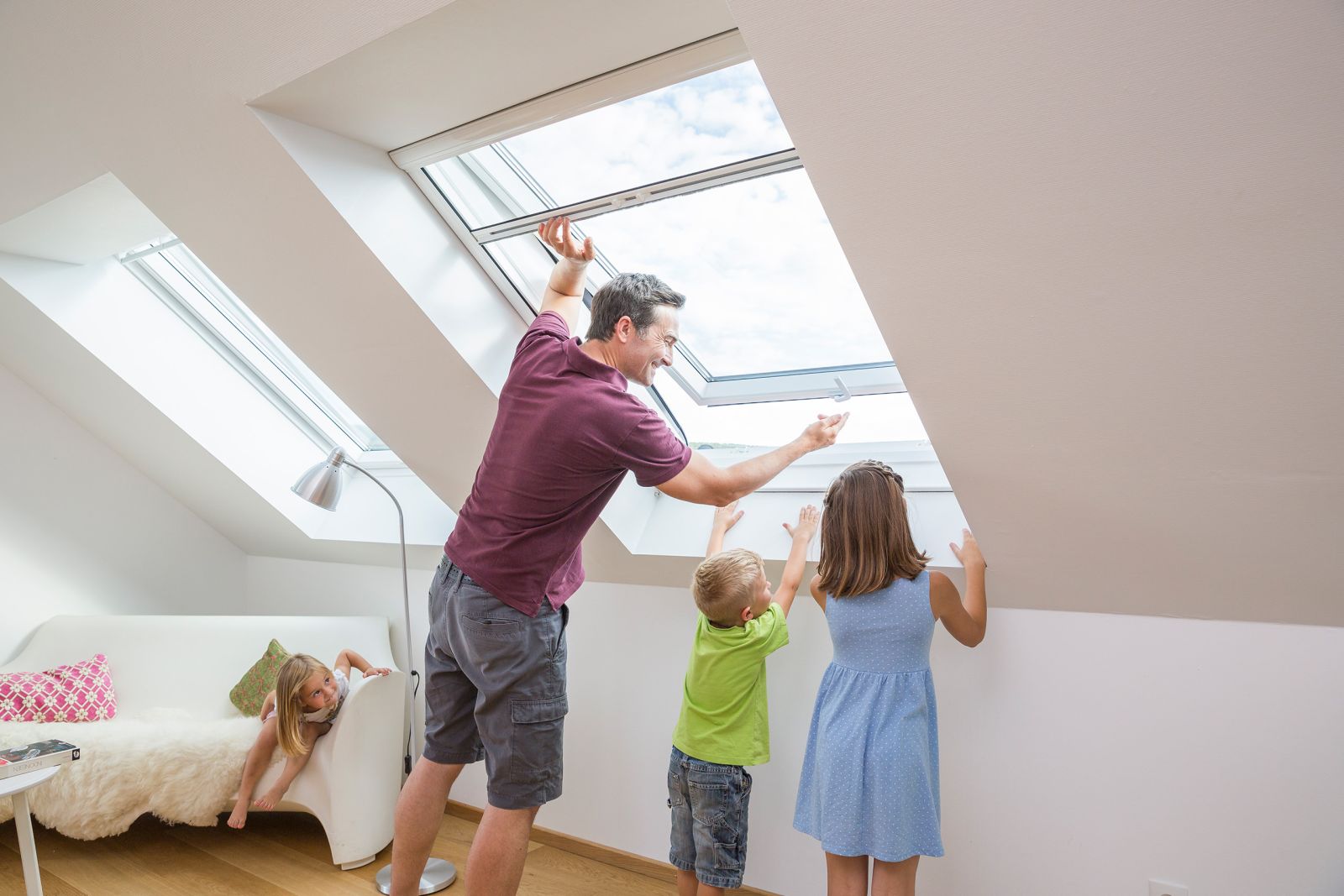 Mann mit Kindern steht an Dachfenster mit Fliegengitter 